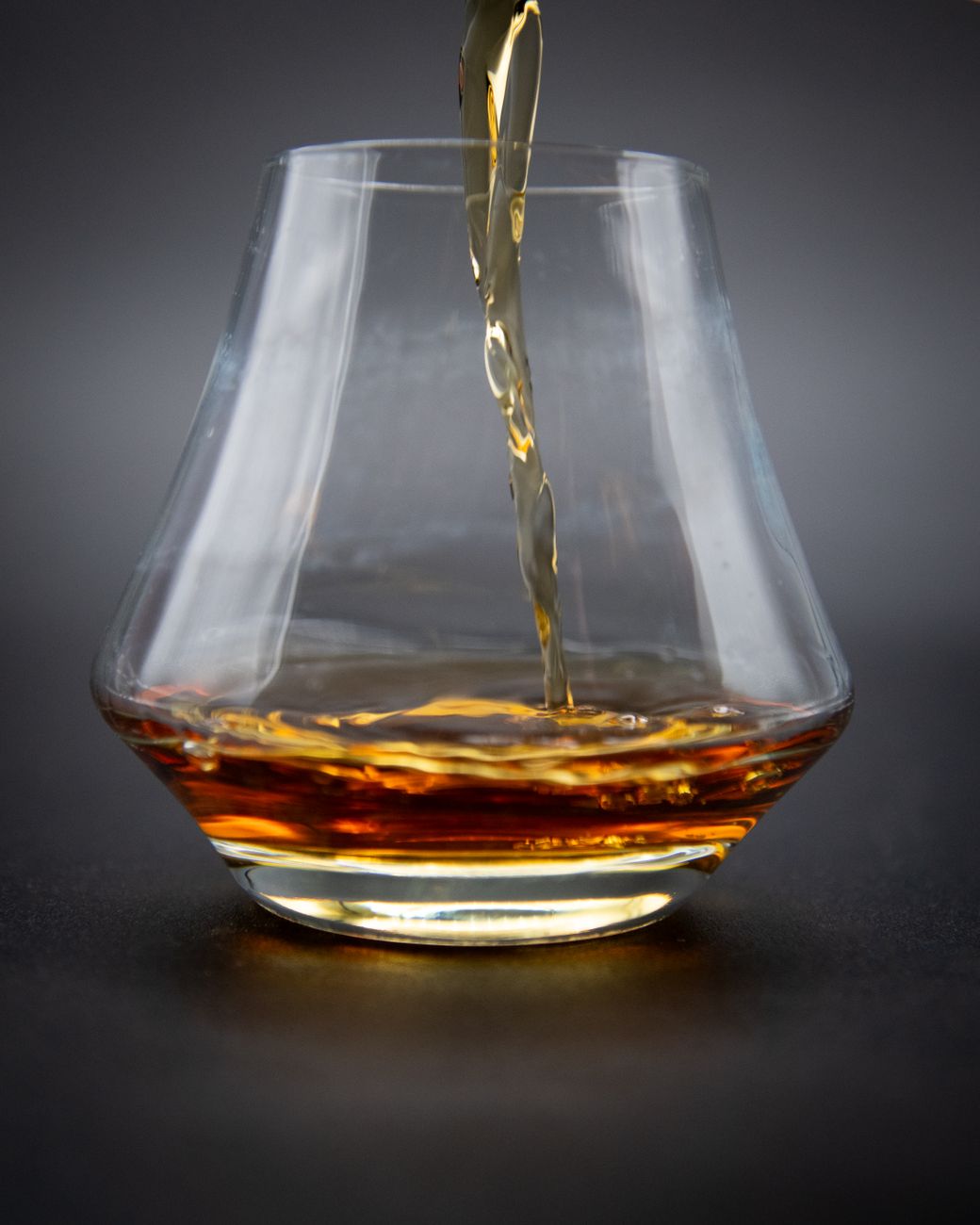 golden whiskey pouring into glass close up